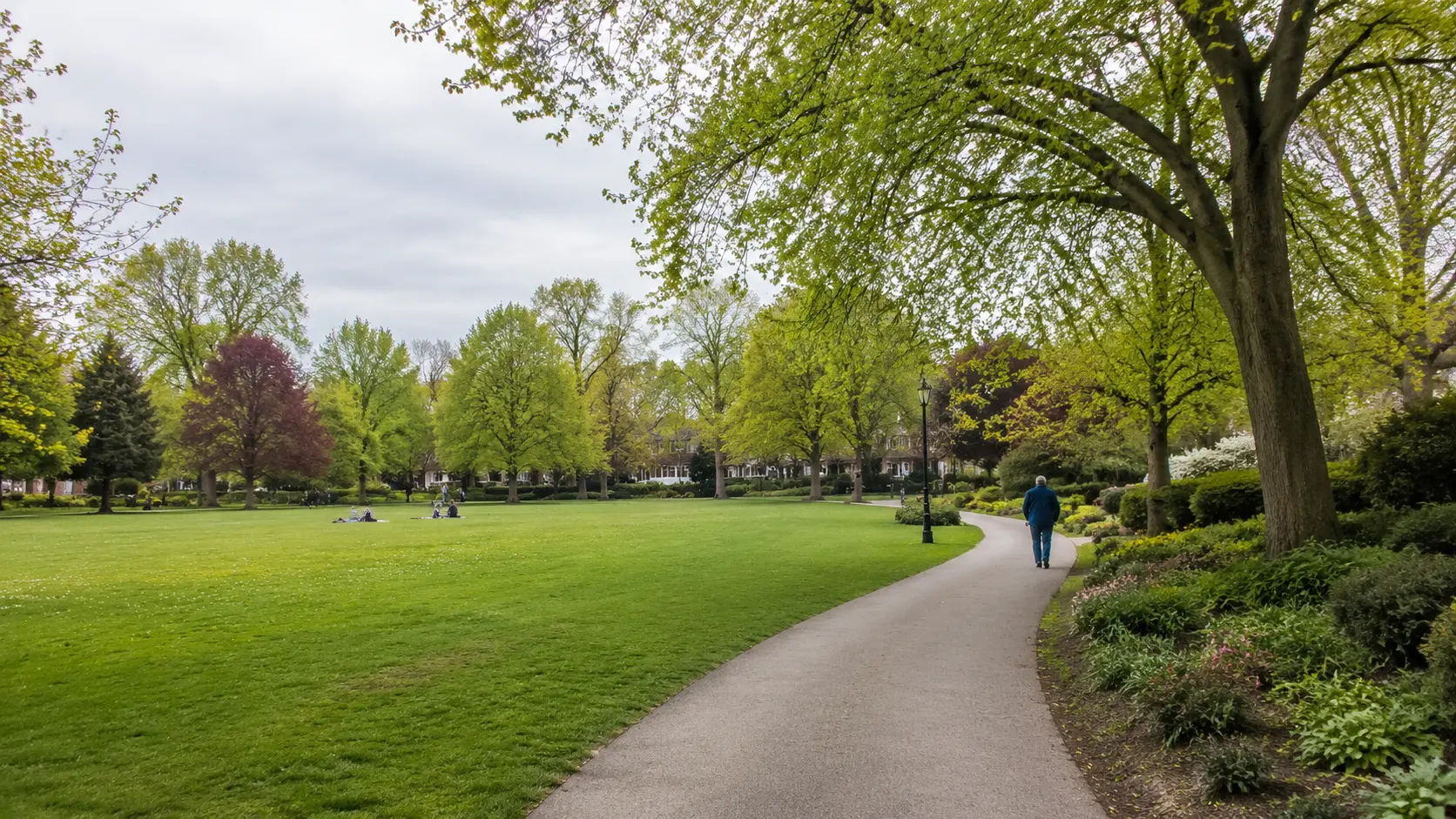 Tree-lined neighbourhood green space with an open lawn and walking path