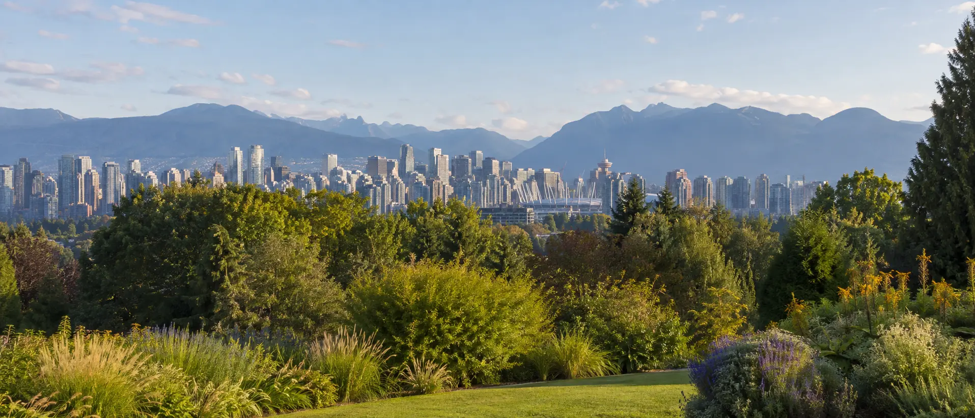 Vancouver skyline and North Shore mountains viewed across landscaped park greenery